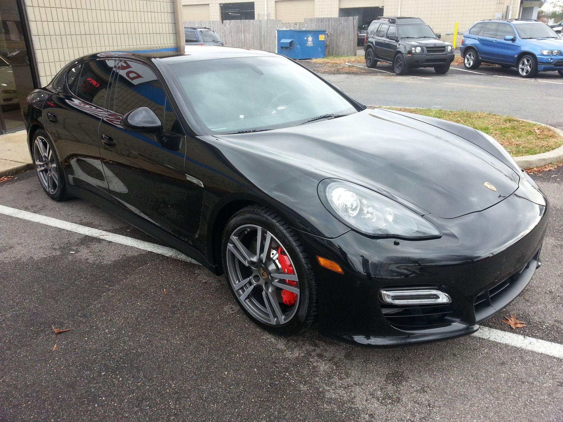 A black porsche panamera is parked in a parking lot.