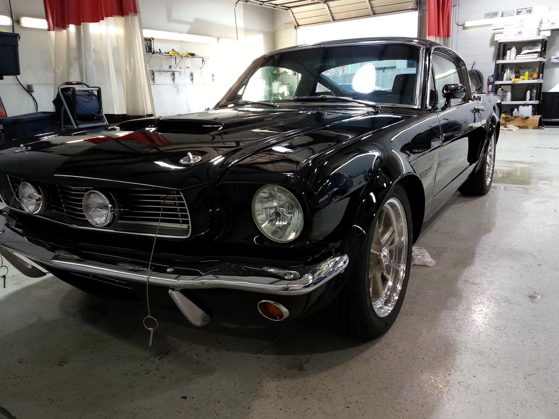 A black mustang is parked in a garage.