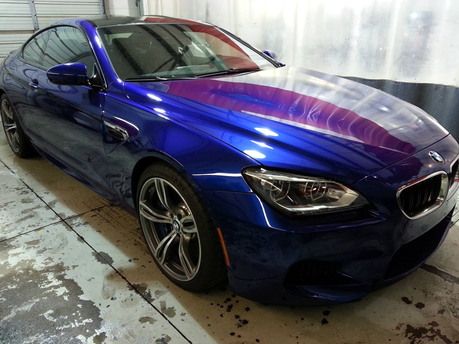 A blue bmw is parked in a garage.