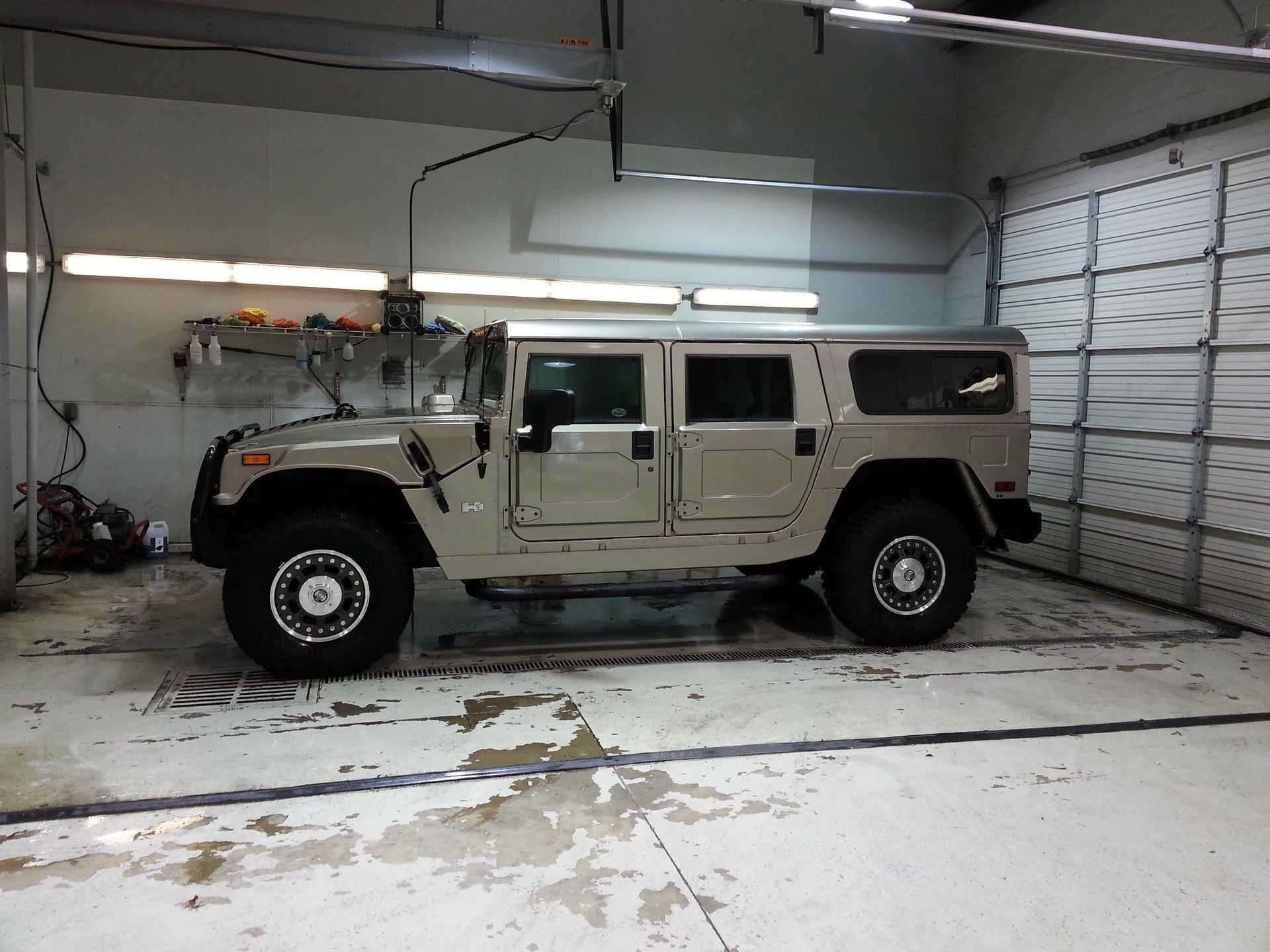 A hummer is parked in a garage next to a garage door.