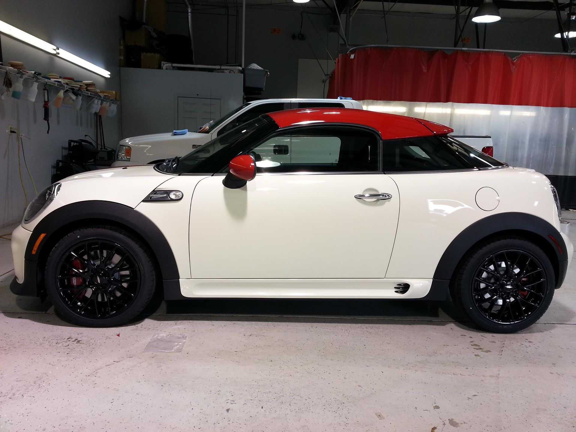 A white car with a red roof is parked in a garage.