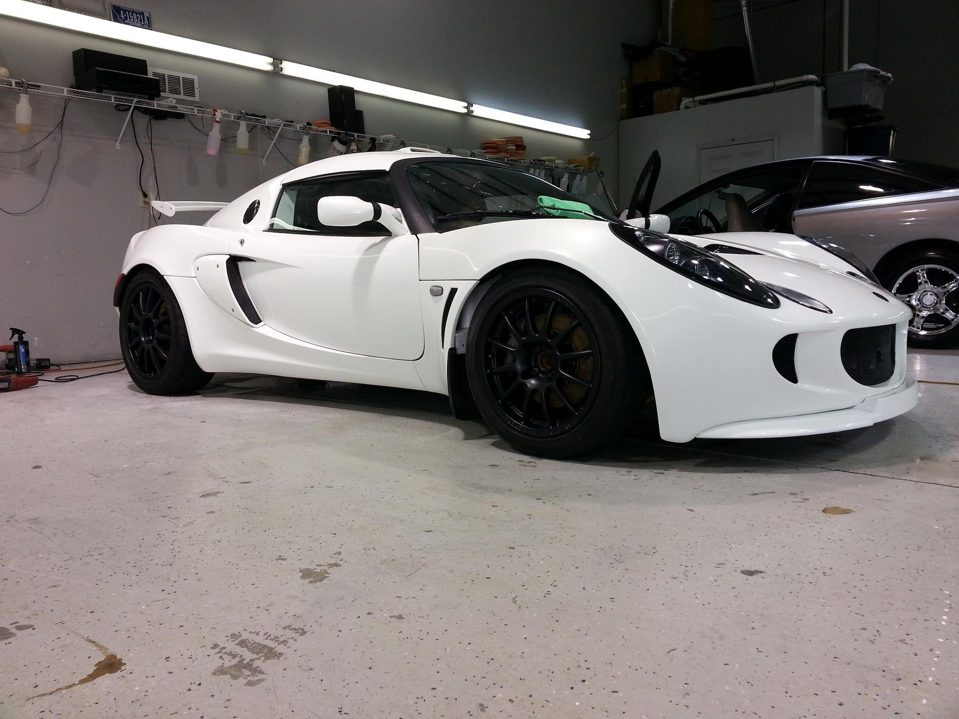 A white sports car is parked in a garage.