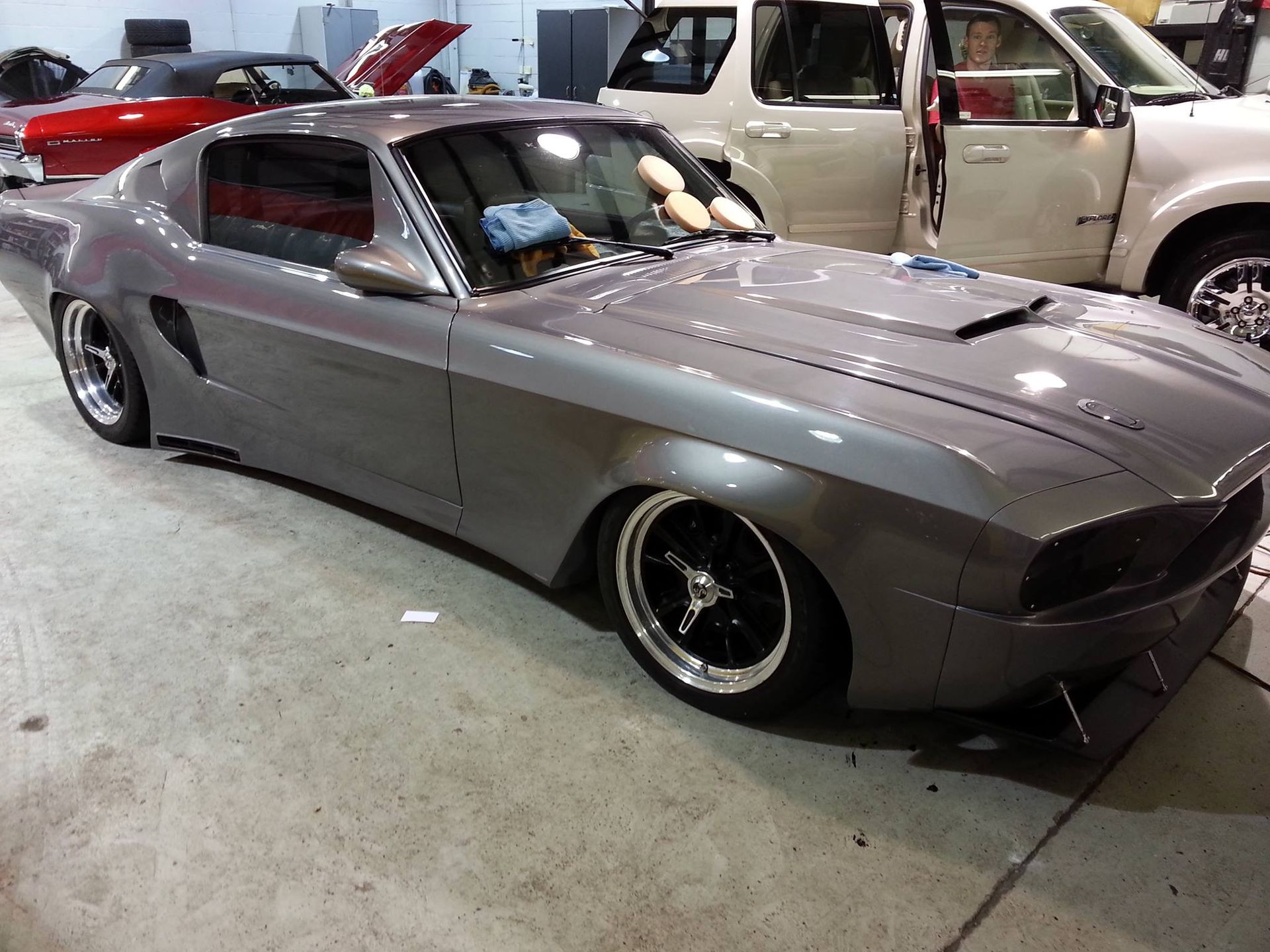 A gray car is parked in a garage with other cars.