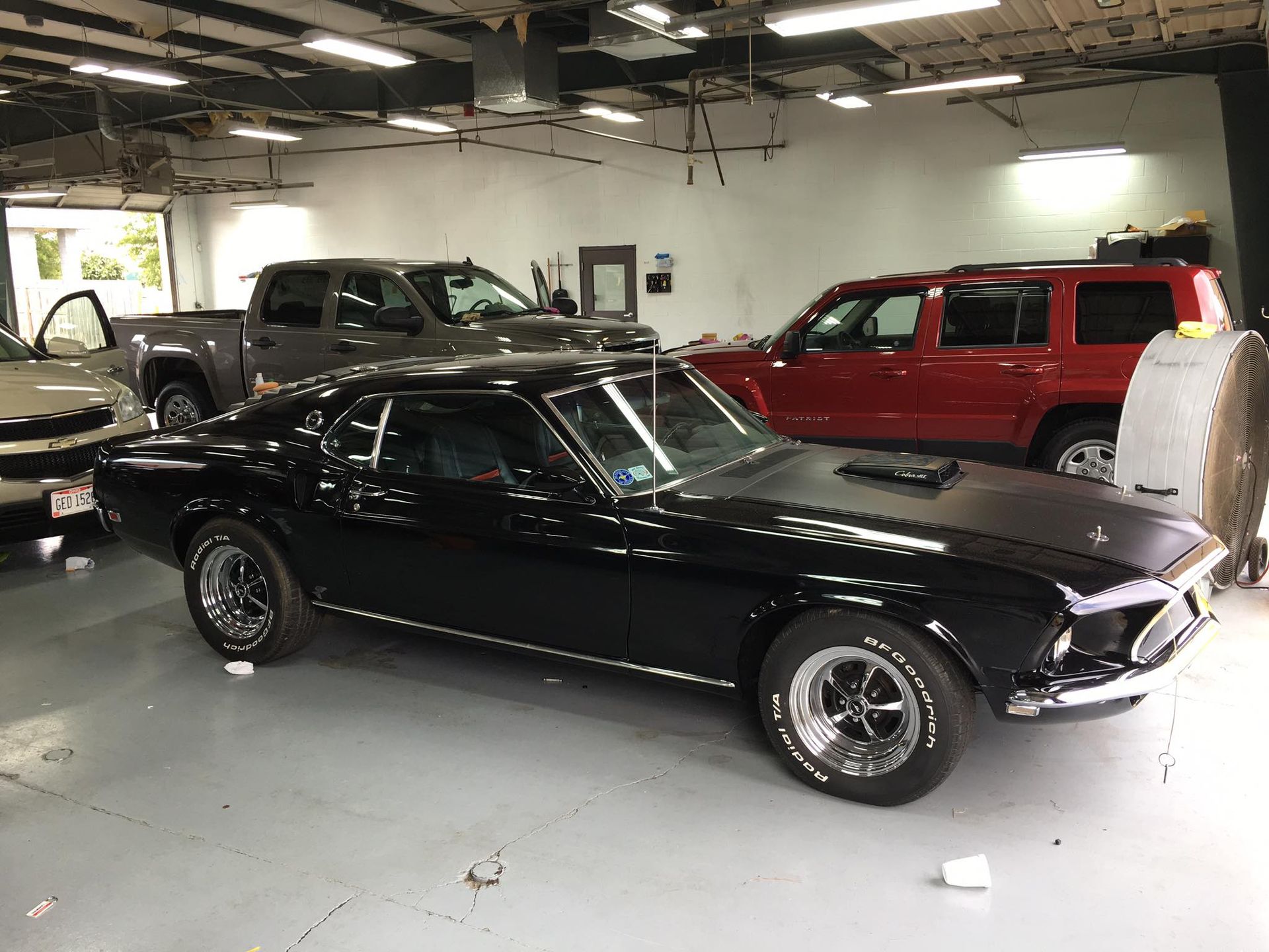 A black mustang is parked in a garage with other cars.