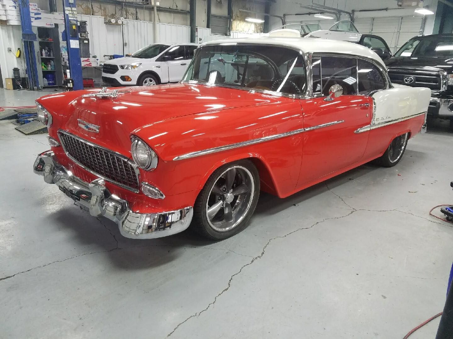 A red and white classic car is parked in a garage.