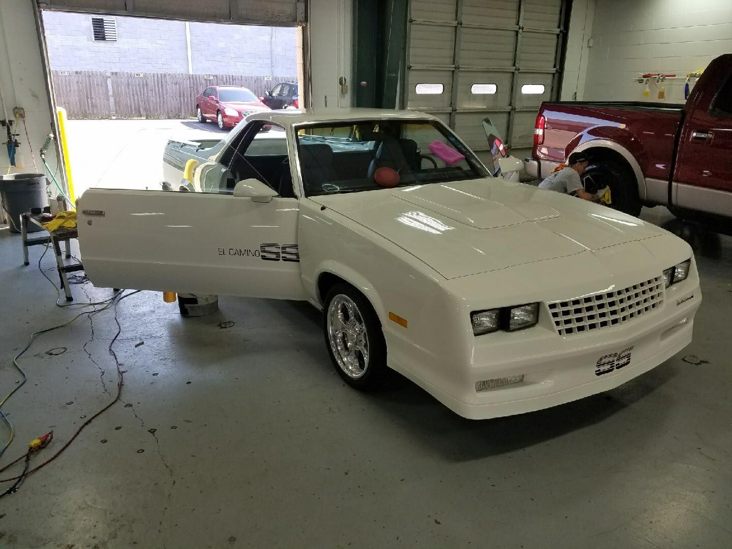 A white car is parked in a garage with its doors open.