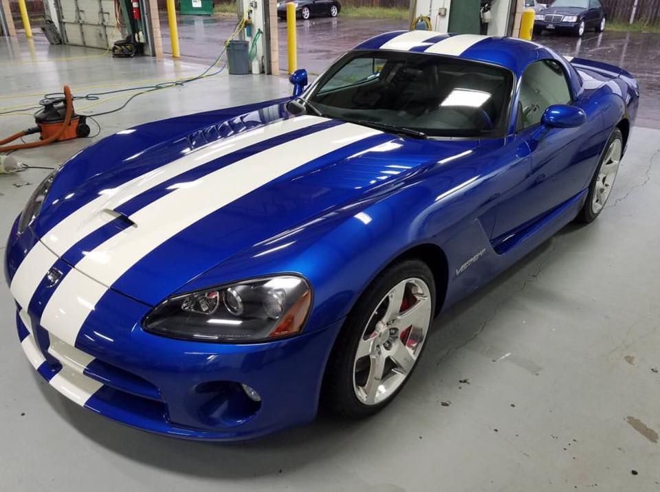 A blue dodge viper with white stripes is parked in a garage.