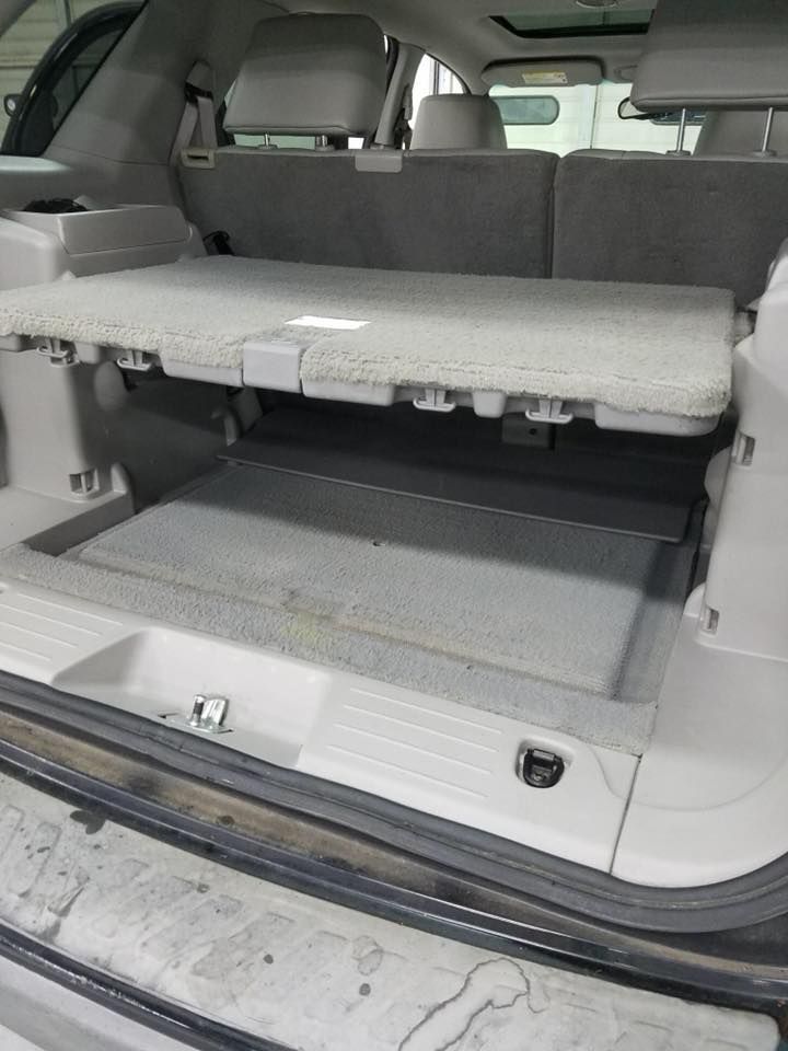 The trunk of a car with a shelf in it.