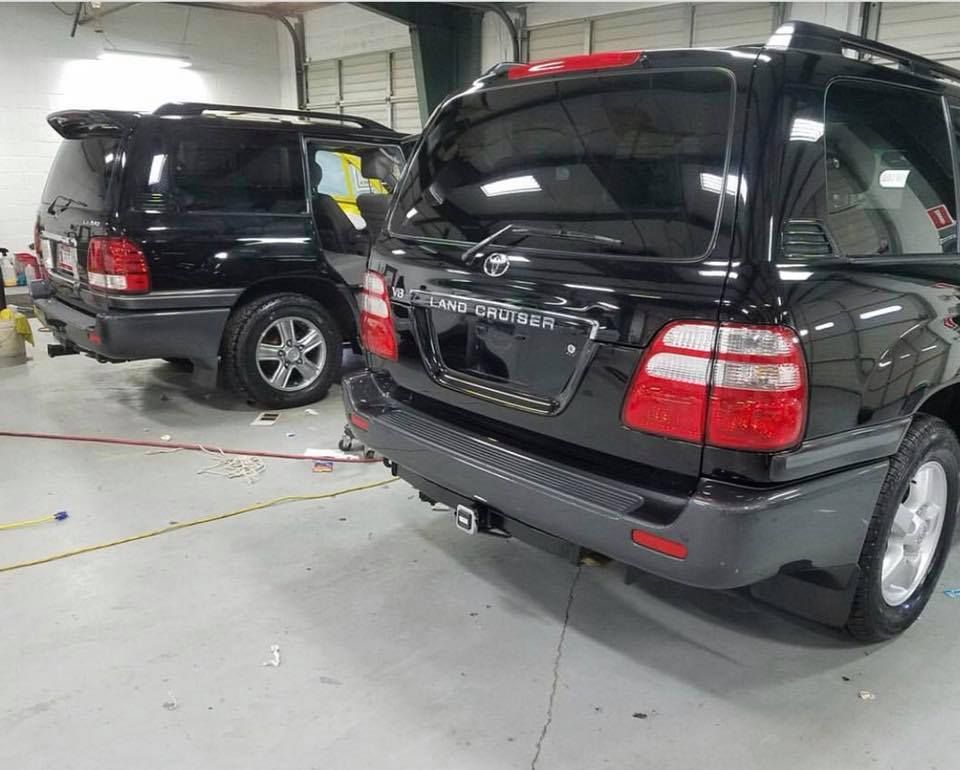 Two black suvs are parked next to each other in a garage.