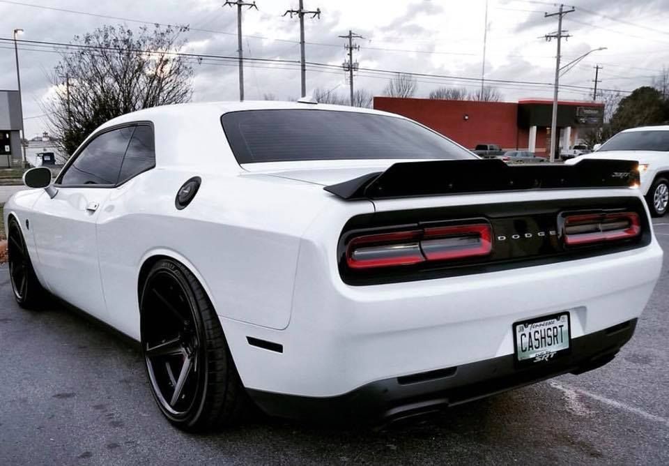 A white dodge challenger is parked in a parking lot.