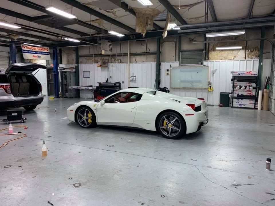 A white sports car is parked in a garage.