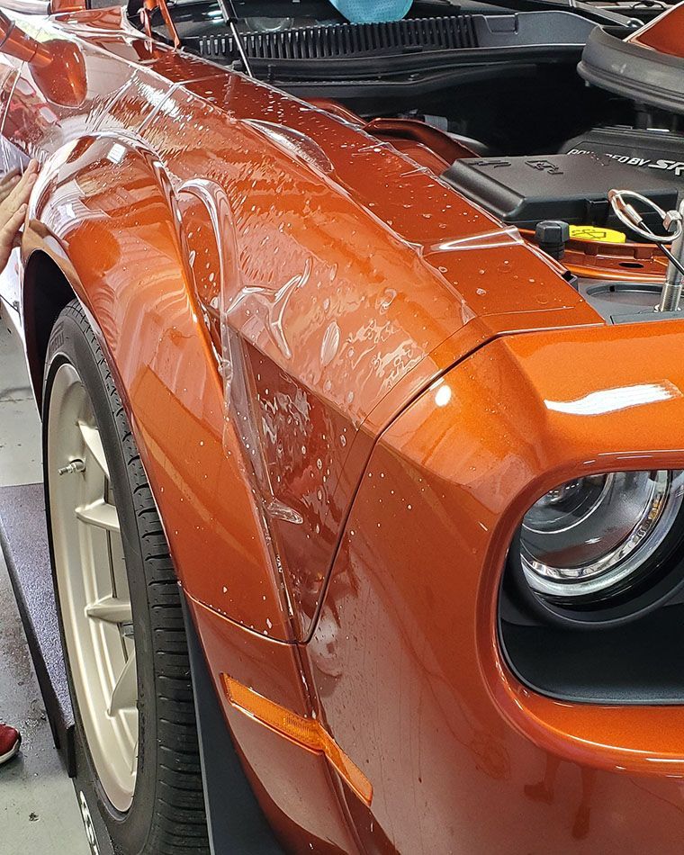 A close up of an orange car with the hood open.