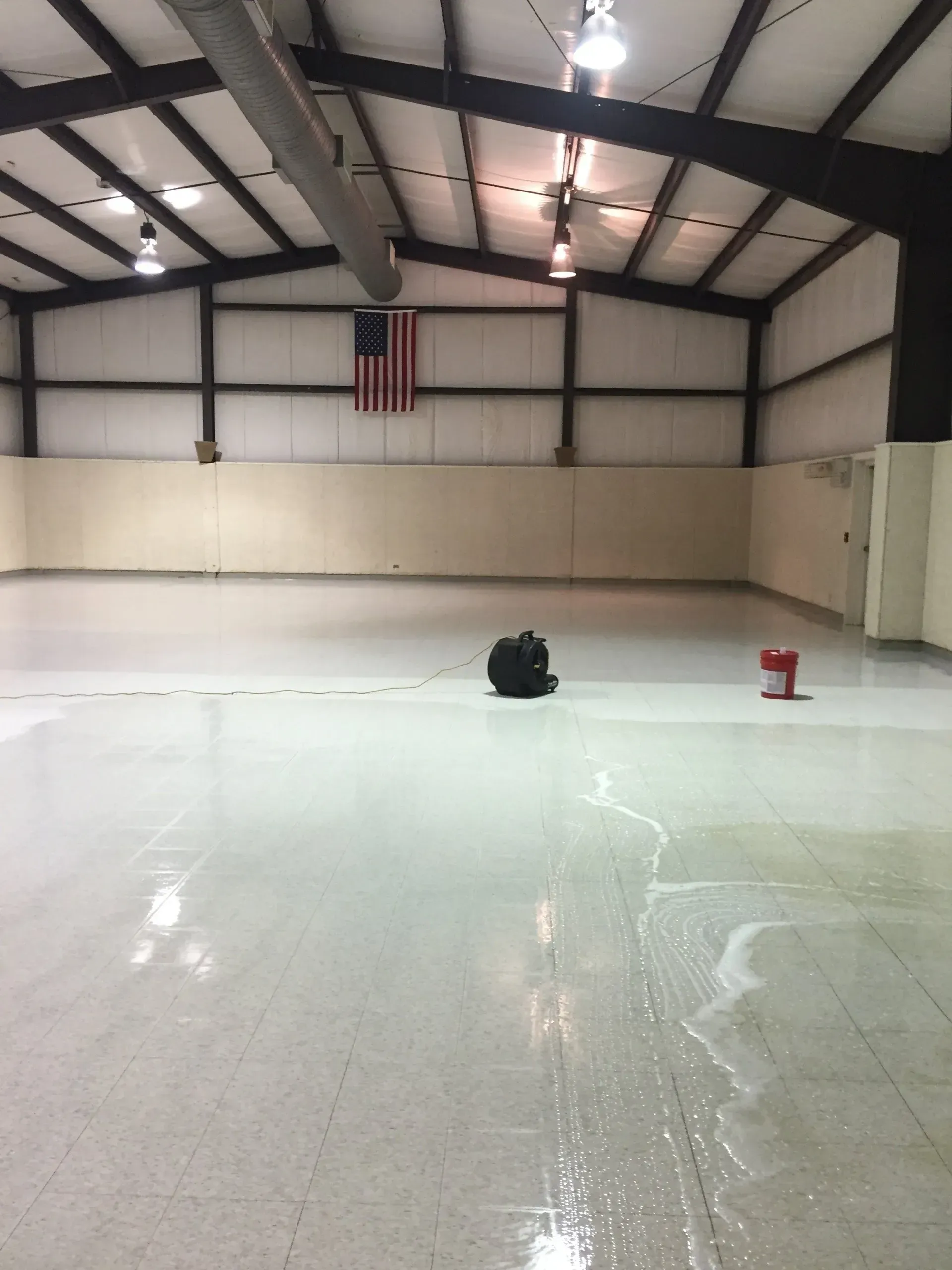 Empty indoor ice rink with American flag, black bag, and red bucket.
