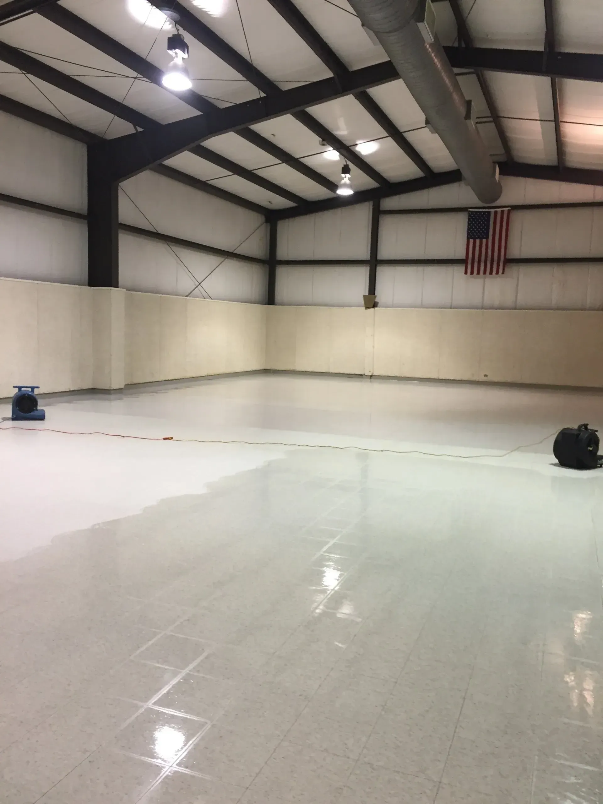 Empty ice rink with reflective surface. An American flag hangs on a wall.