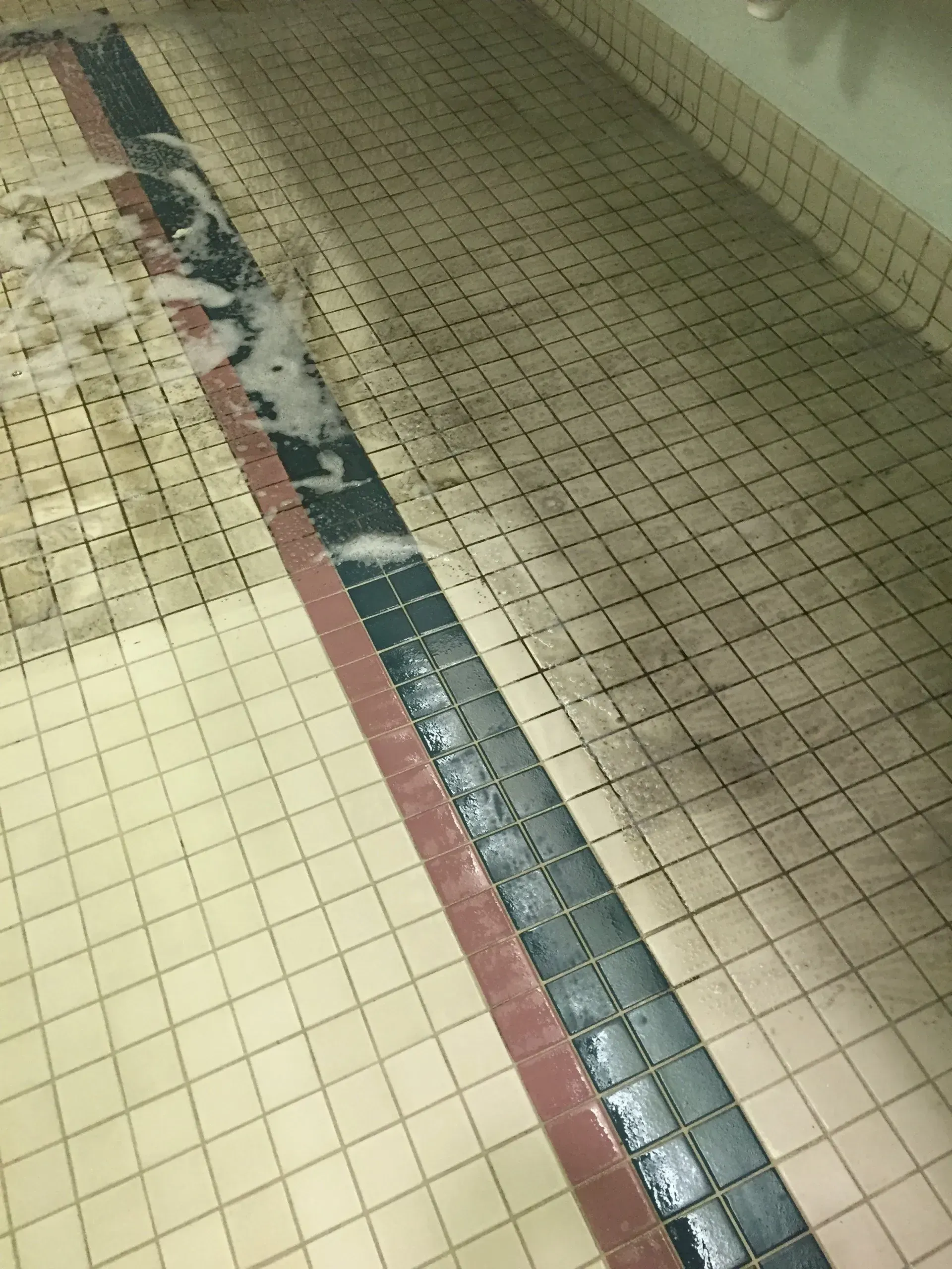 Pool floor with a water channel, tiled with dirt and bubbles.