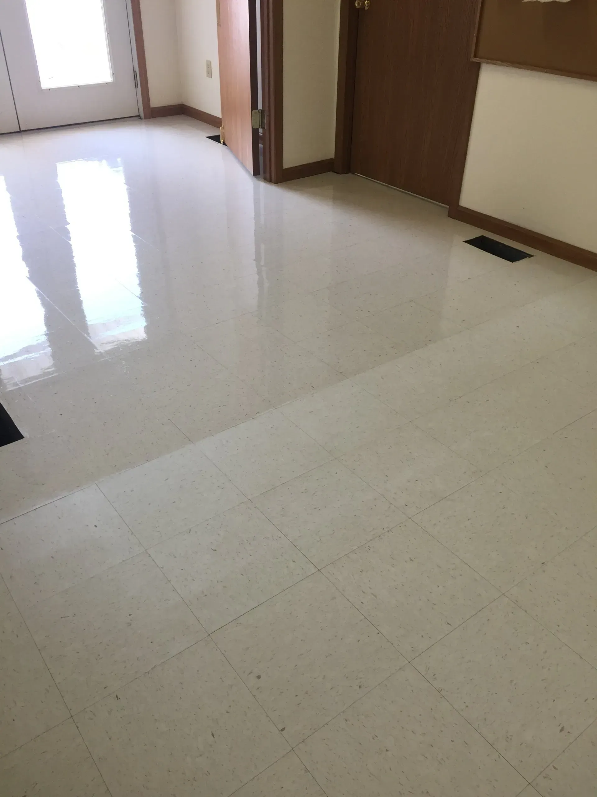 Bright, tiled floor with a noticeable transition. A doorway, door, and wall are visible in the room.