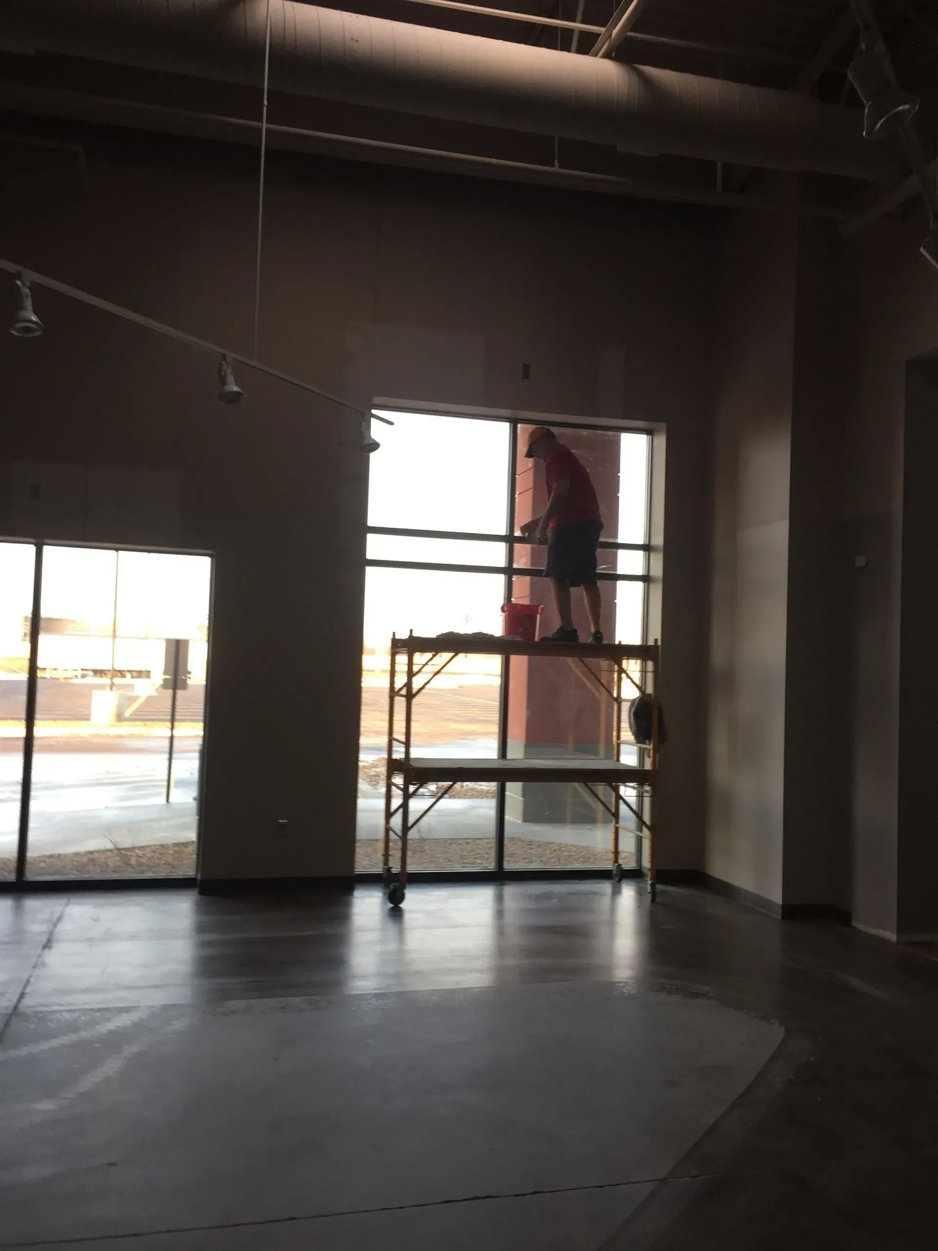 Person on scaffolding cleaning large window in a commercial building.