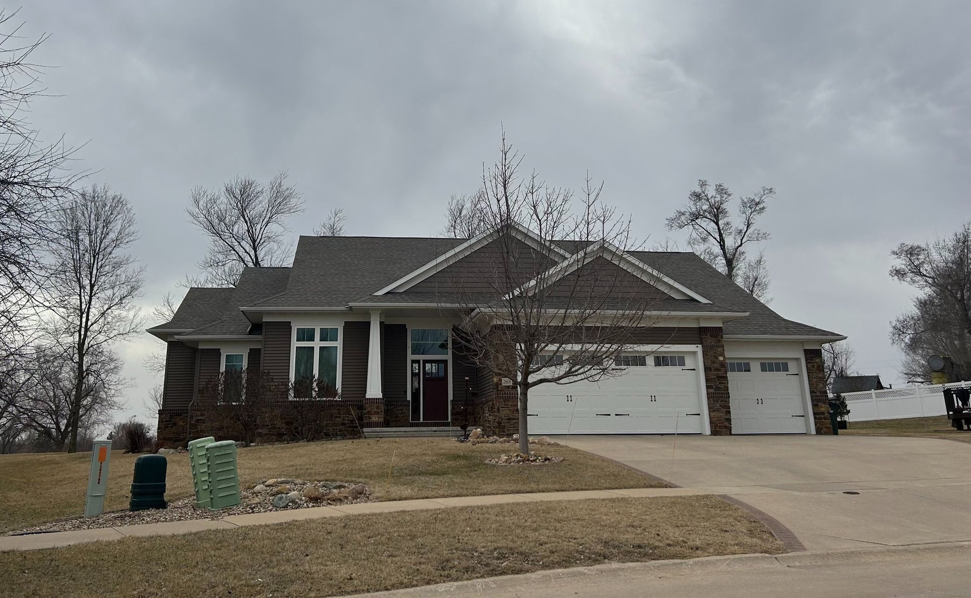 Suburban house with brick facade and attached garage under cloudy sky.