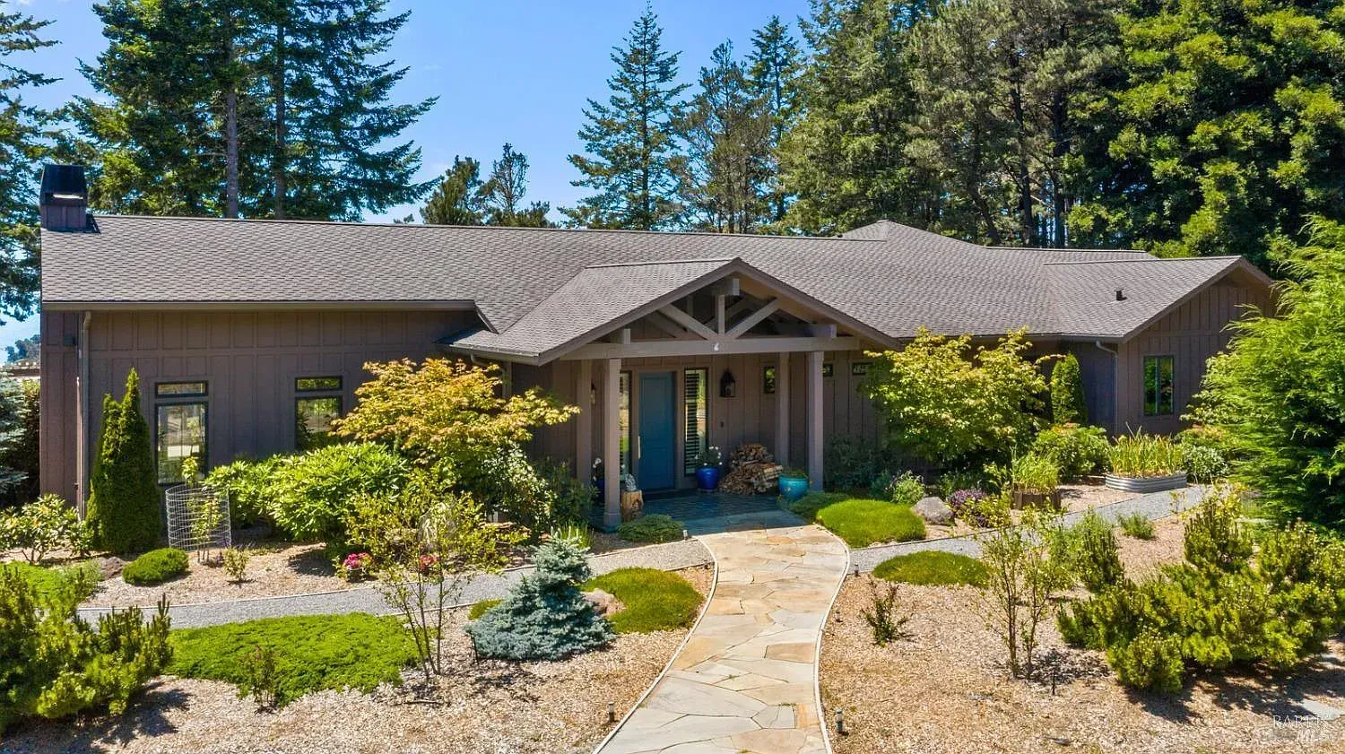 a large house with a gray roof is surrounded by trees and bushes