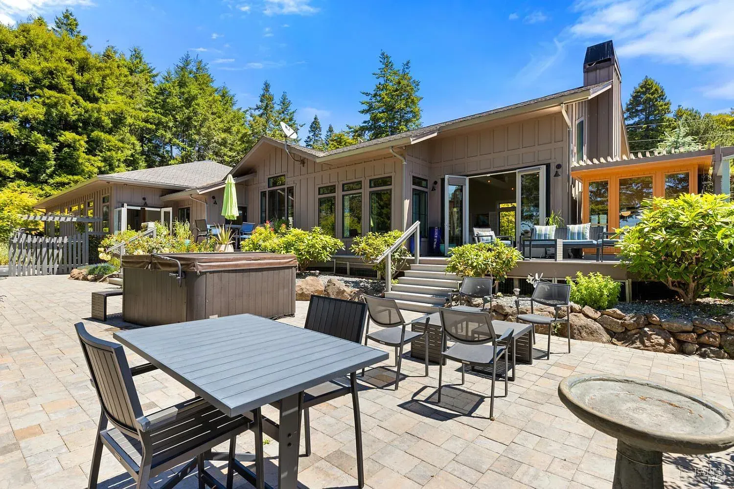 there is a table and chairs on the patio in front of the house