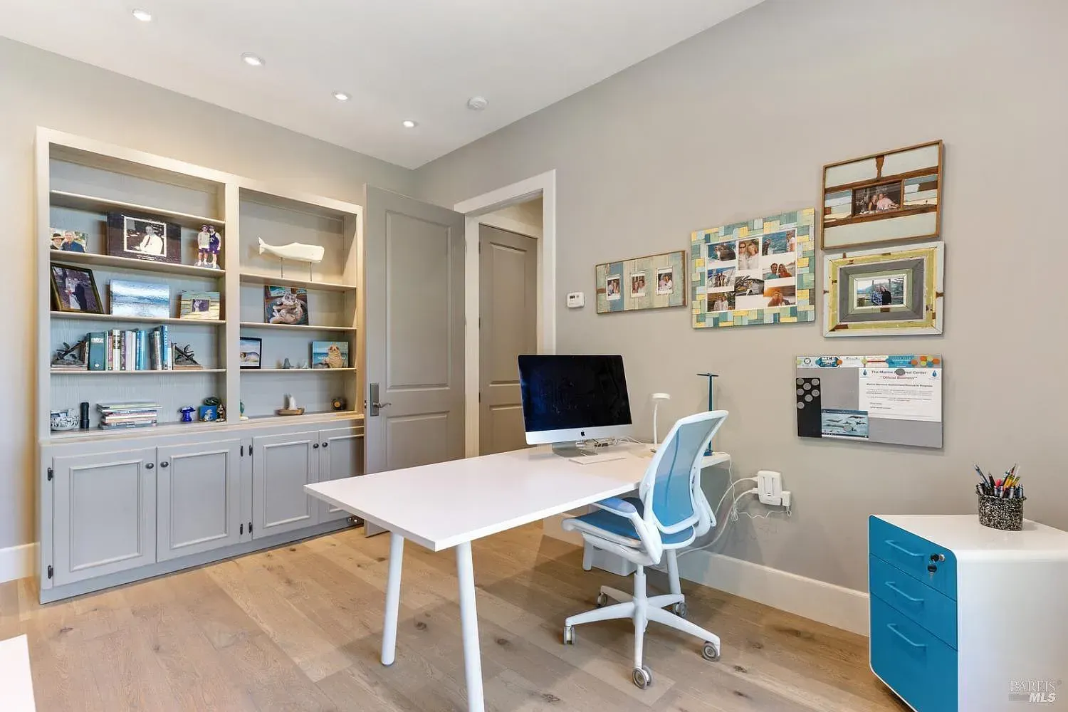 a home office with a desk, chair, computer and shelves