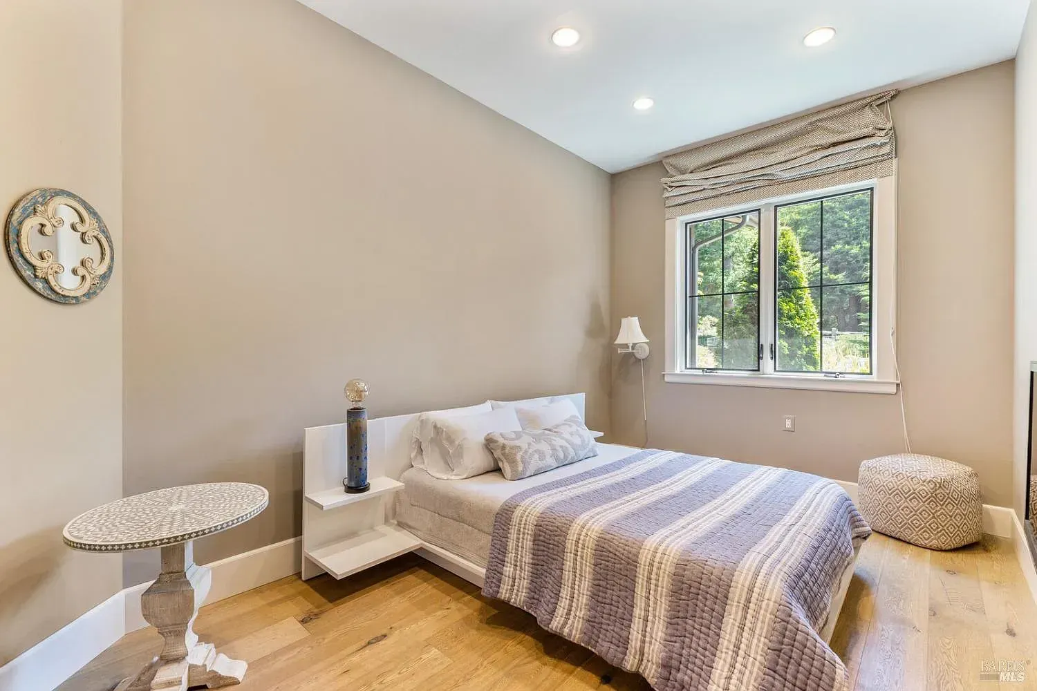 a bedroom with a bed, table, lamp and window