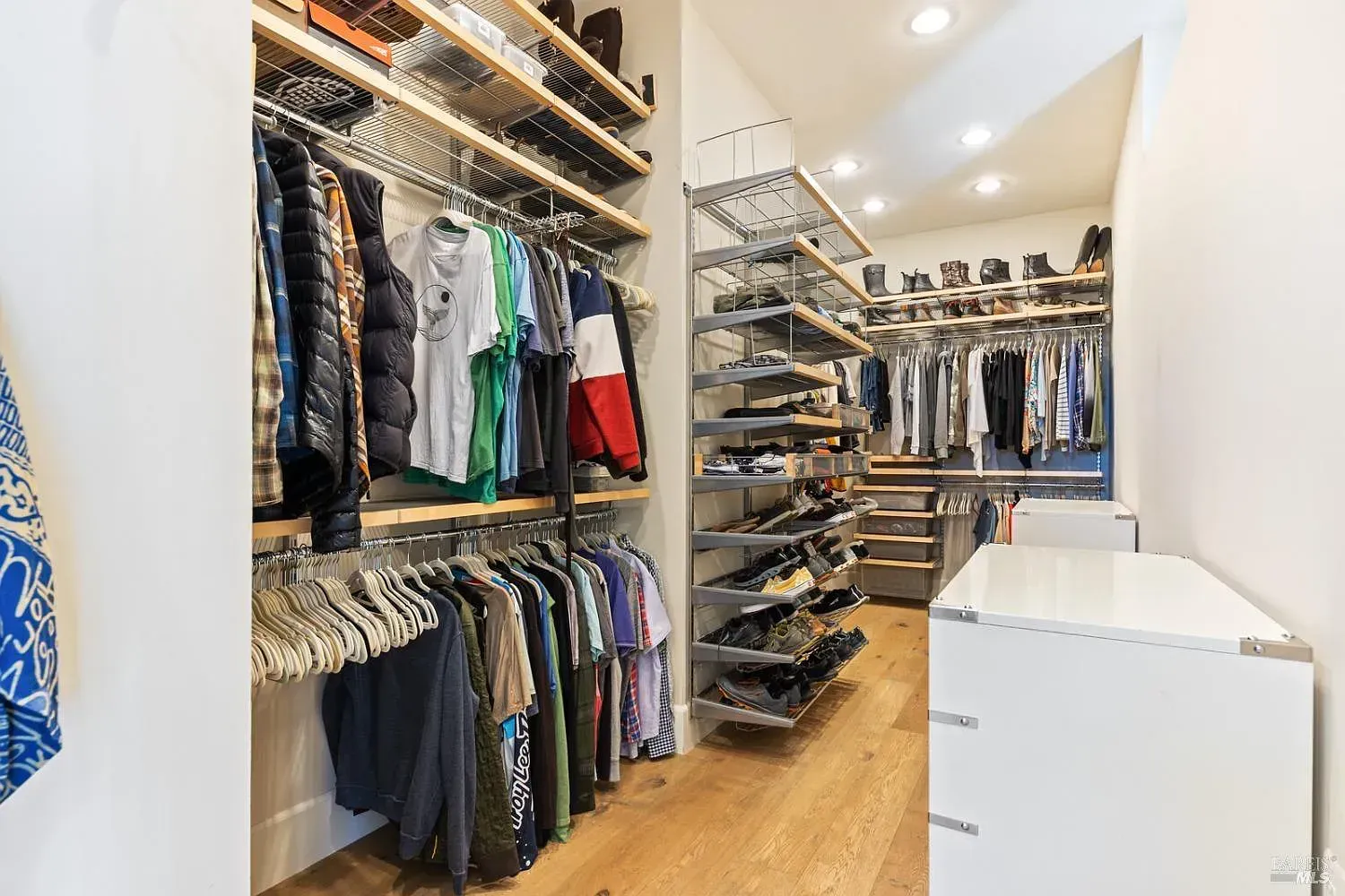 a walk-in closet filled with lots of clothes and shoes