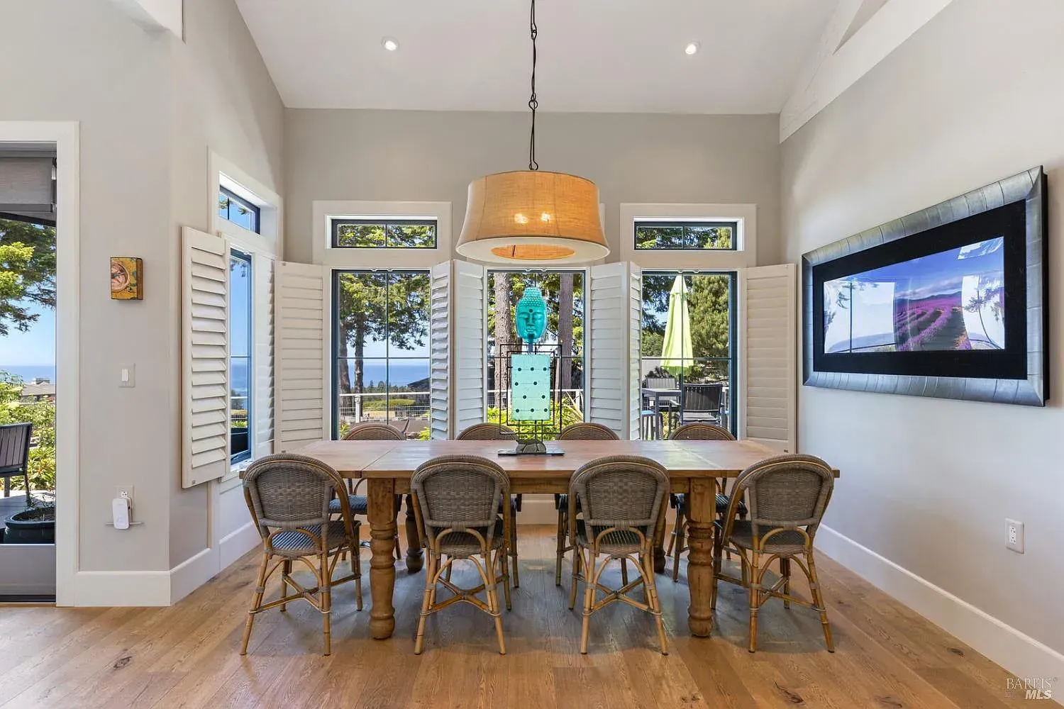 a dining room with a table and chairs and a large picture on the wall
