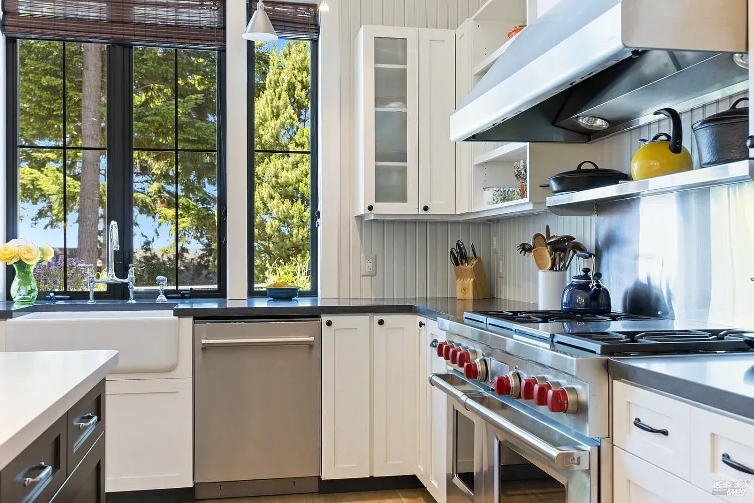 a kitchen with white cabinets, stainless steel appliances, a stove, and a sink