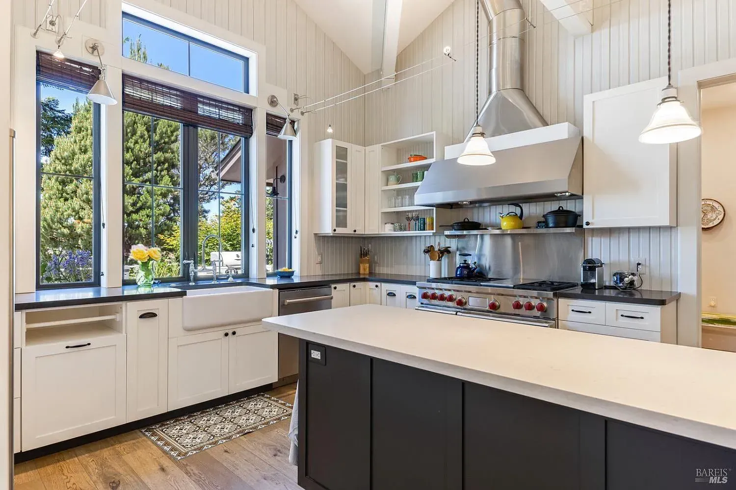 a kitchen with white cabinets, black cabinets, stainless steel appliances, and a large island