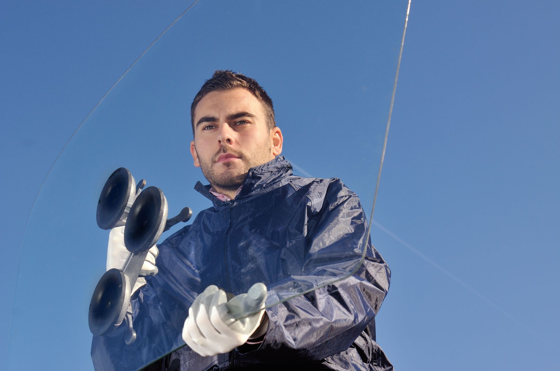 Man in a blue jacket holding a weather instrument against a clear blue sky