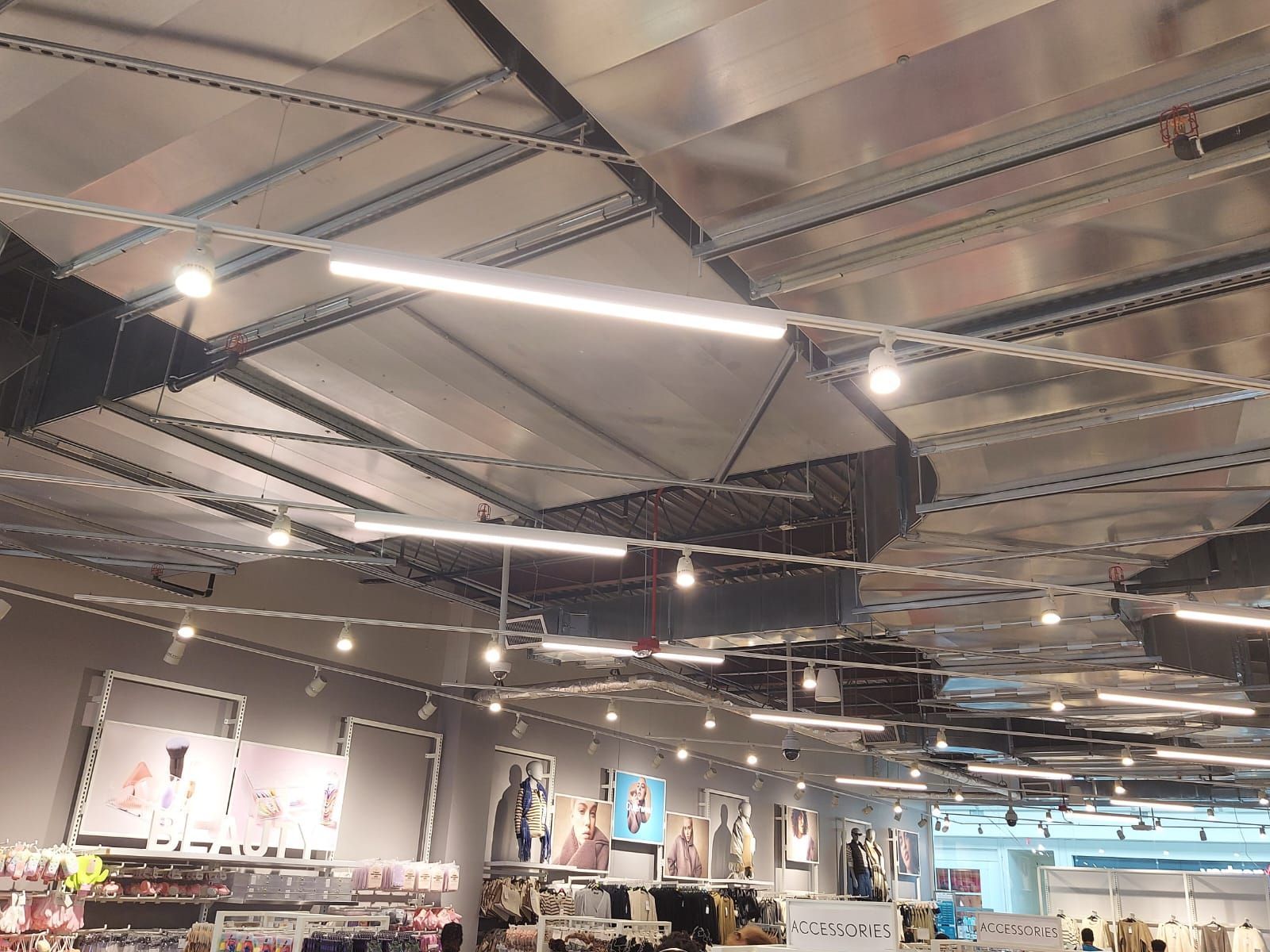 Clothing store interior with racks of apparel, hanging lights, and exposed metal ceiling beams