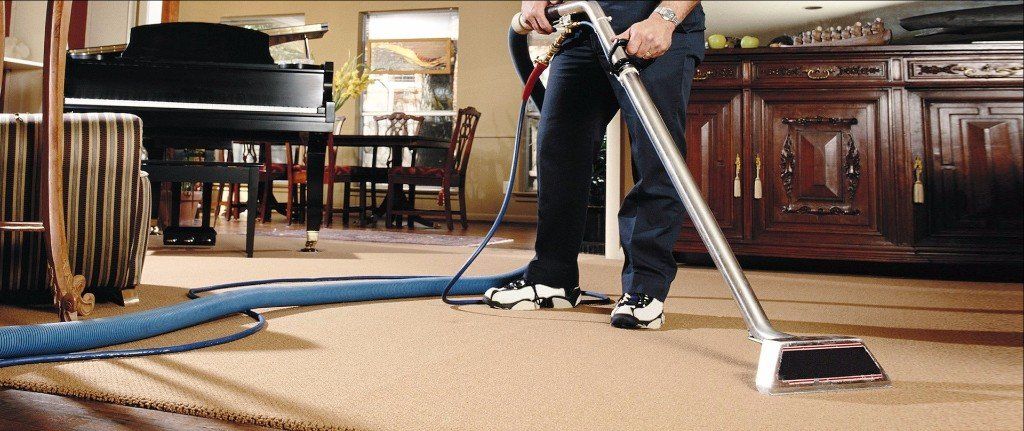 A man is using a vacuum cleaner to clean a carpet in a living room.