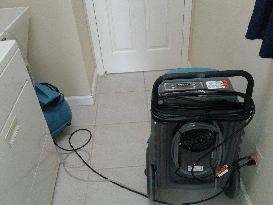 A vacuum cleaner is sitting in a laundry room next to a washer and dryer