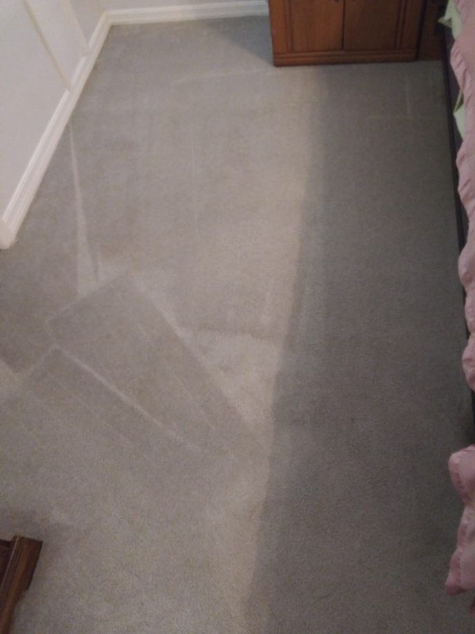 A bedroom with a gray carpeted floor and a wooden dresser.