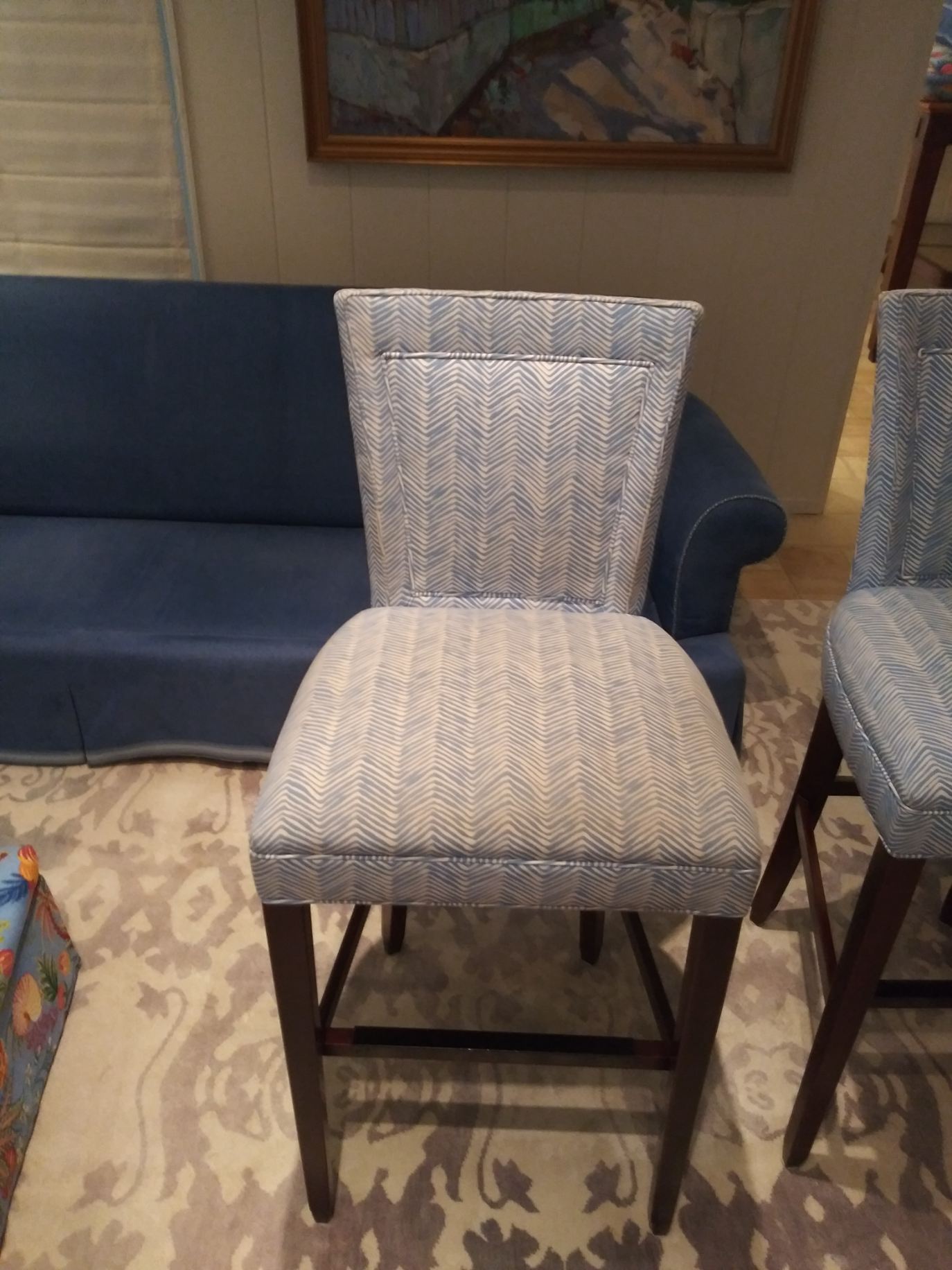 Two chairs are sitting next to a blue couch in a living room.