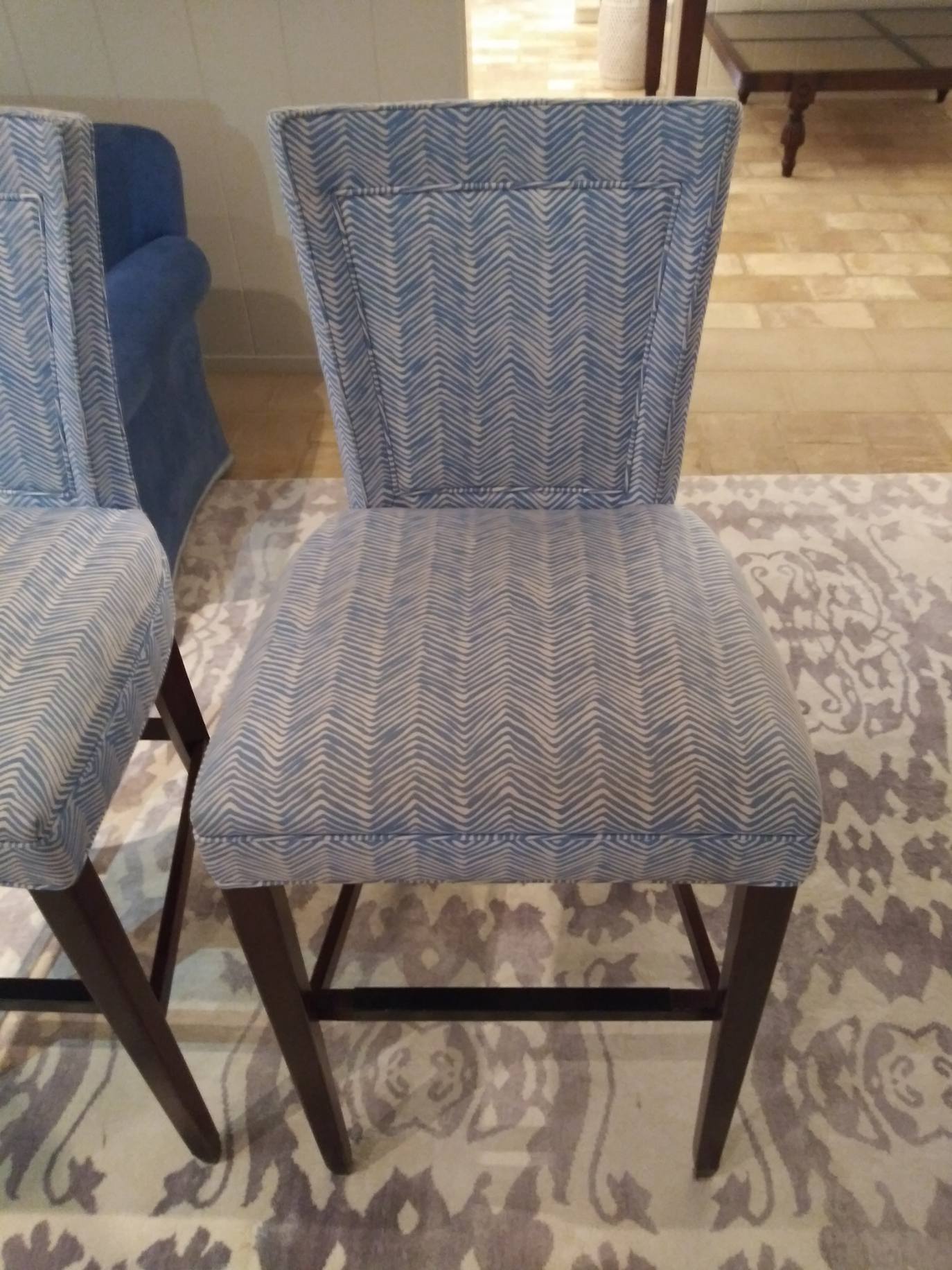 Two blue chairs are sitting next to each other on a rug.
