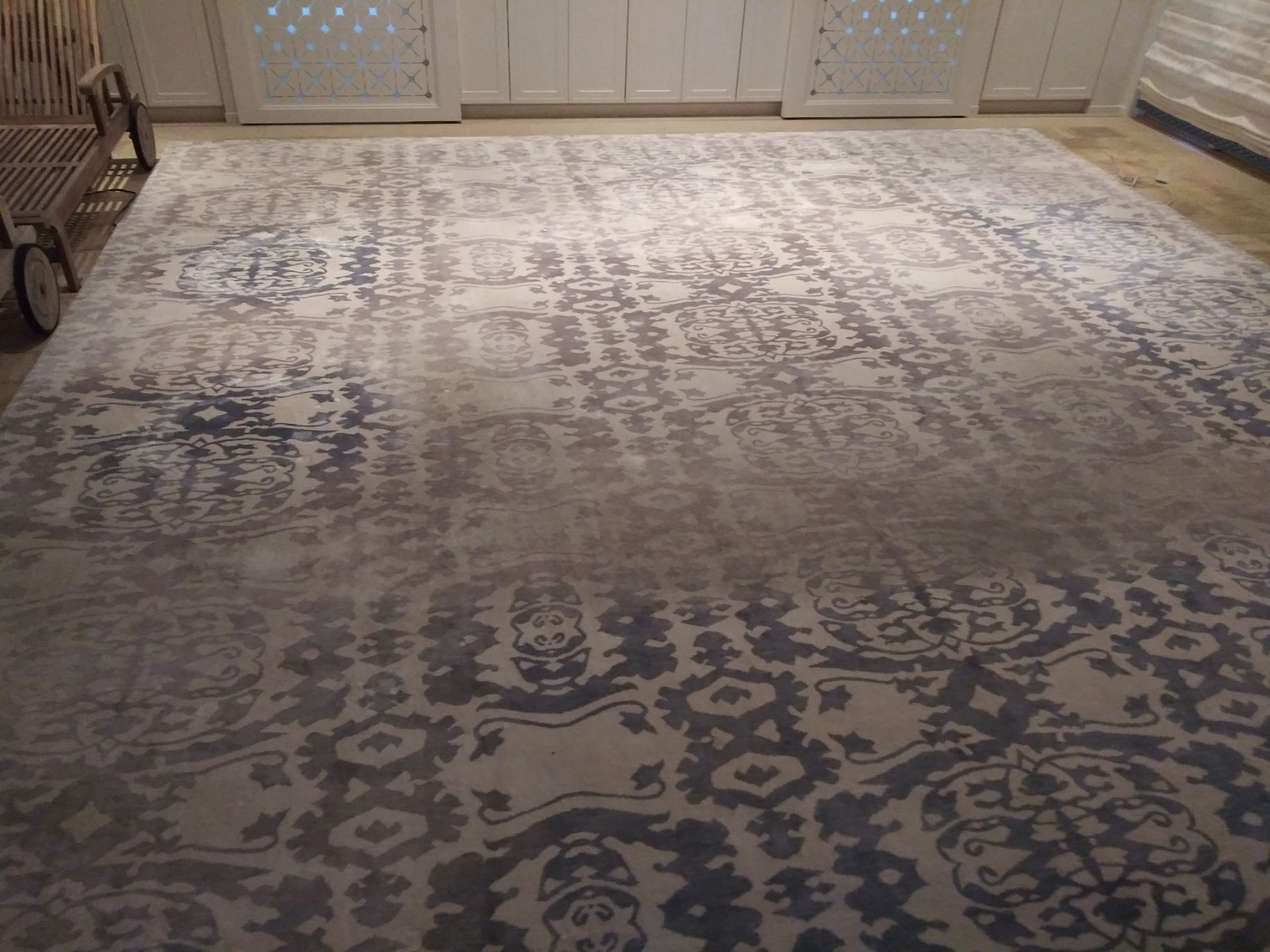 A large rug is sitting on the floor in a room.