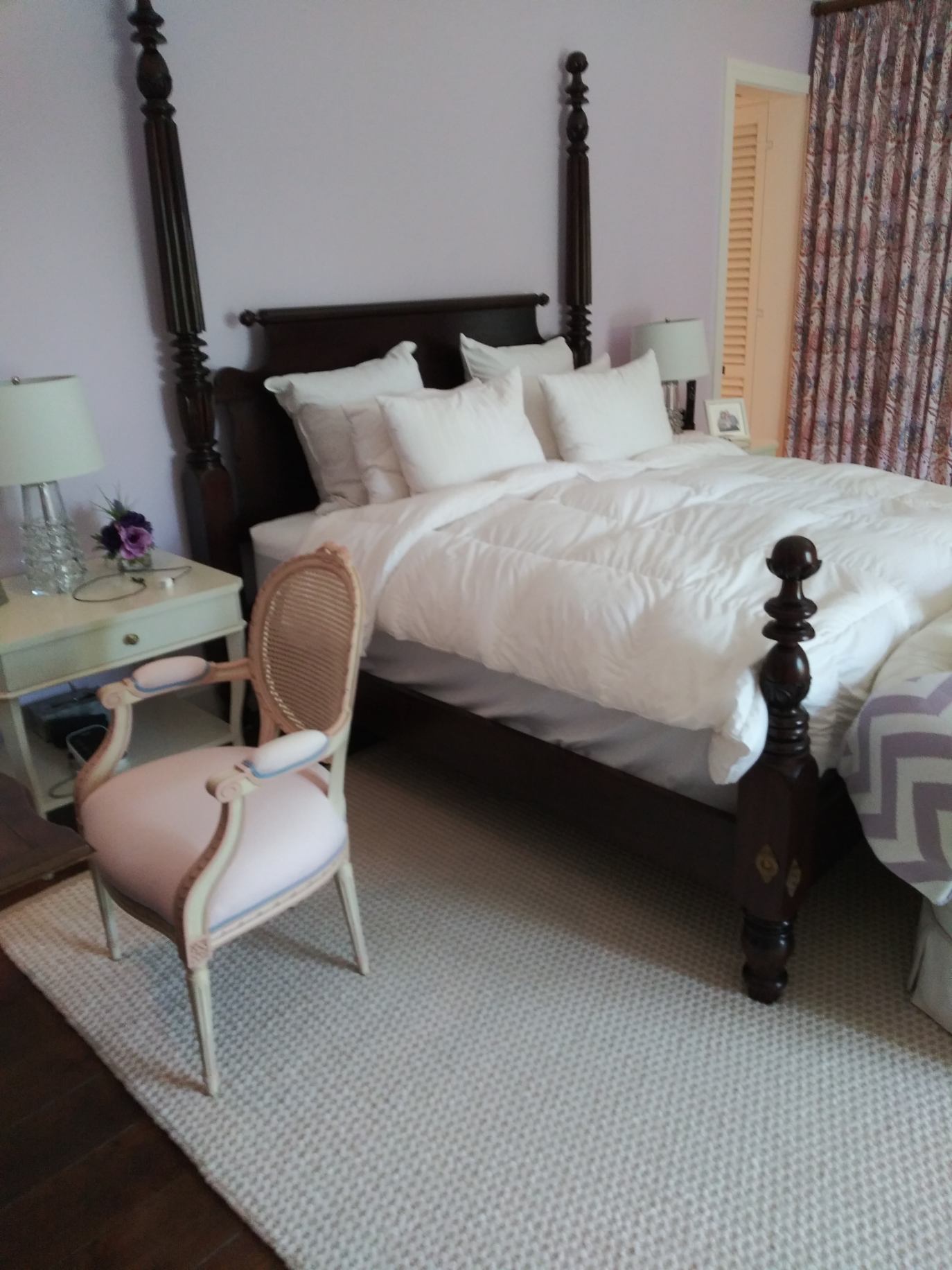 A bedroom with a four poster bed and a chair