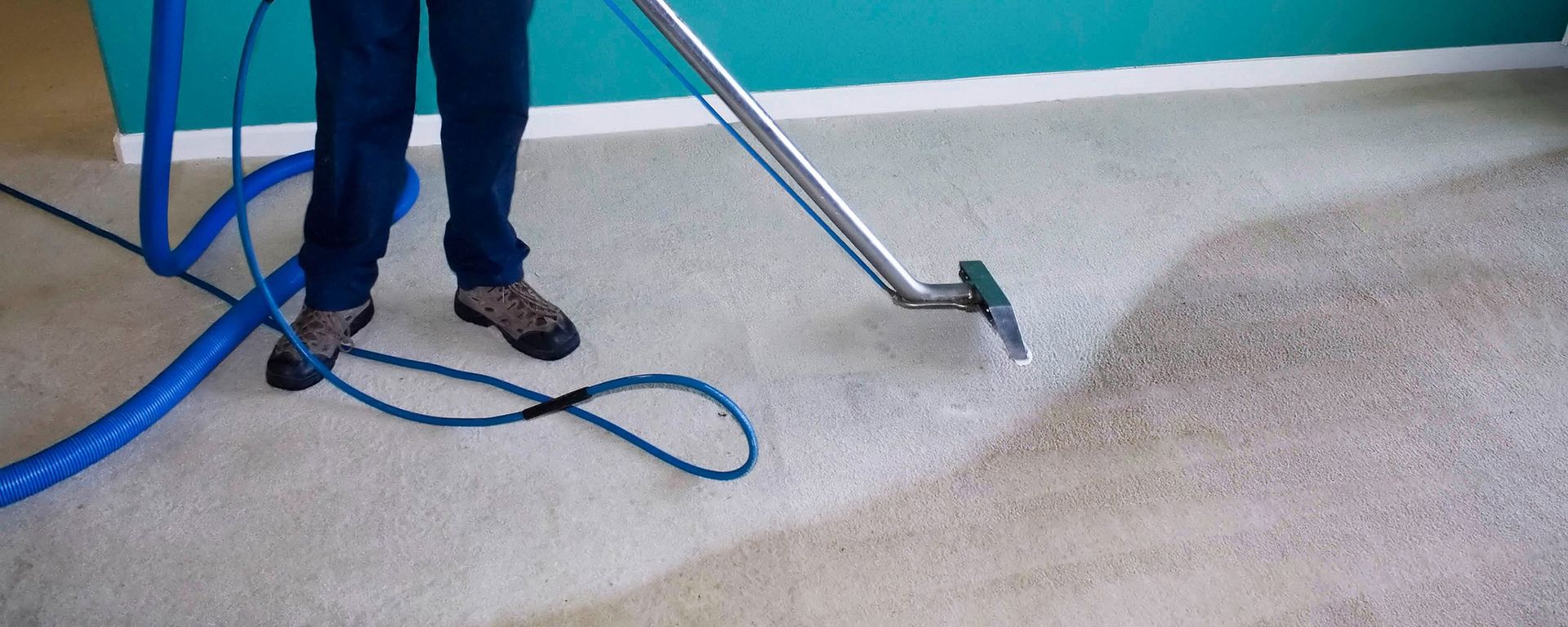 A person is cleaning a carpet with a vacuum cleaner.