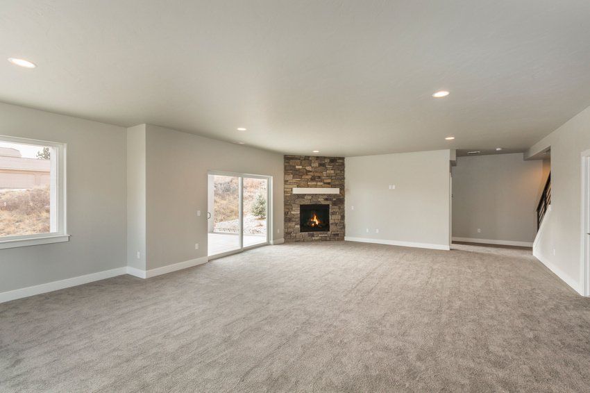 An empty living room with a fireplace and sliding glass doors.