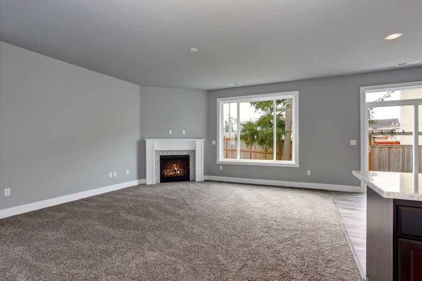 An empty living room with a fireplace and a large window.