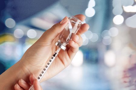 A person is holding a syringe and a bottle of liquid.