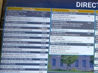 A building directory sign listing businesses and medical offices on the Ground and First Floors with their room numbers.