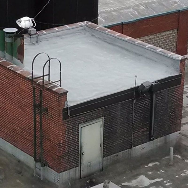 Brick building rooftop with ladder, door, and security light.