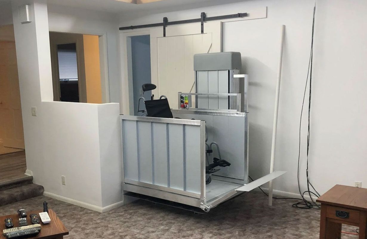 Indoor wheelchair lift, silver, near a white wall and a sliding door.