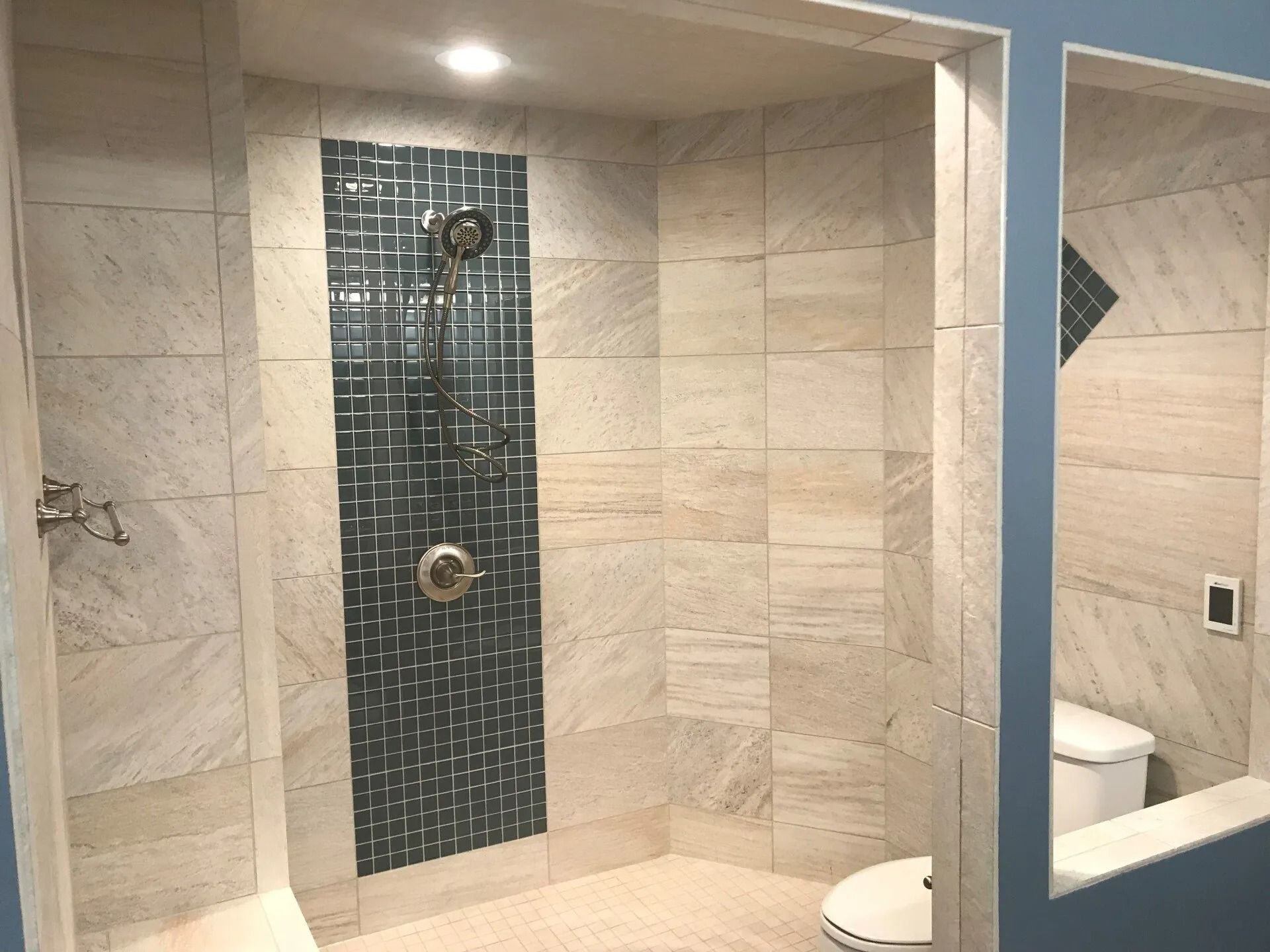 Bathroom with tan tile walls, blue accent wall, and white toilet.
