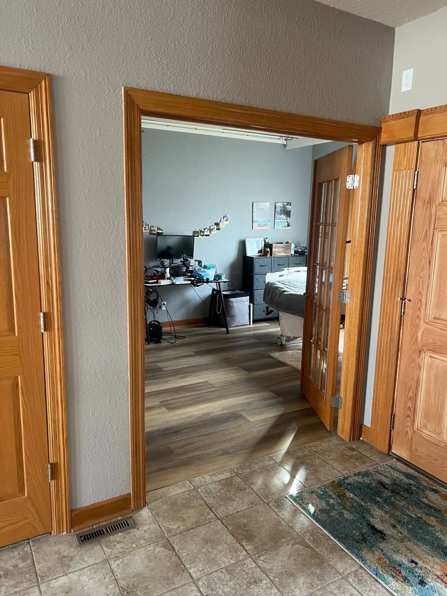 Interior view: doorway to a home office with desk, computer, and other items. Brown wood trim and doors.