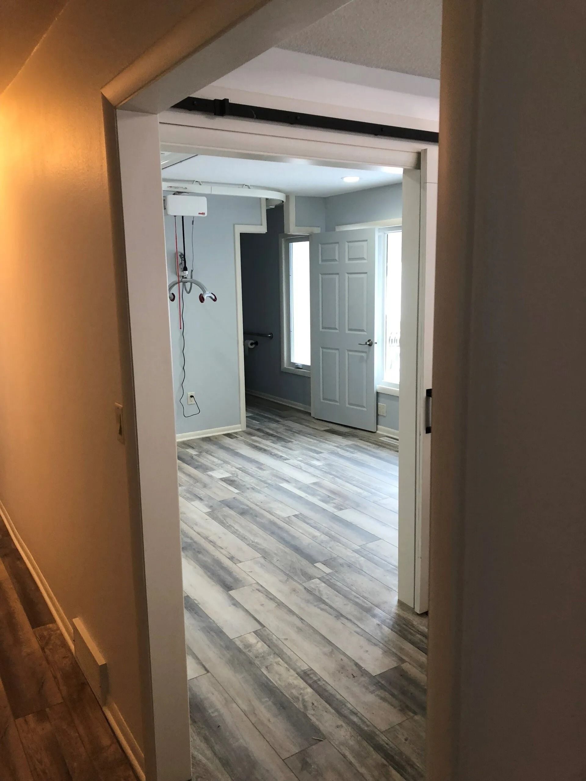 View through doorway into a room with gray flooring, a closed door, and blue-gray walls.