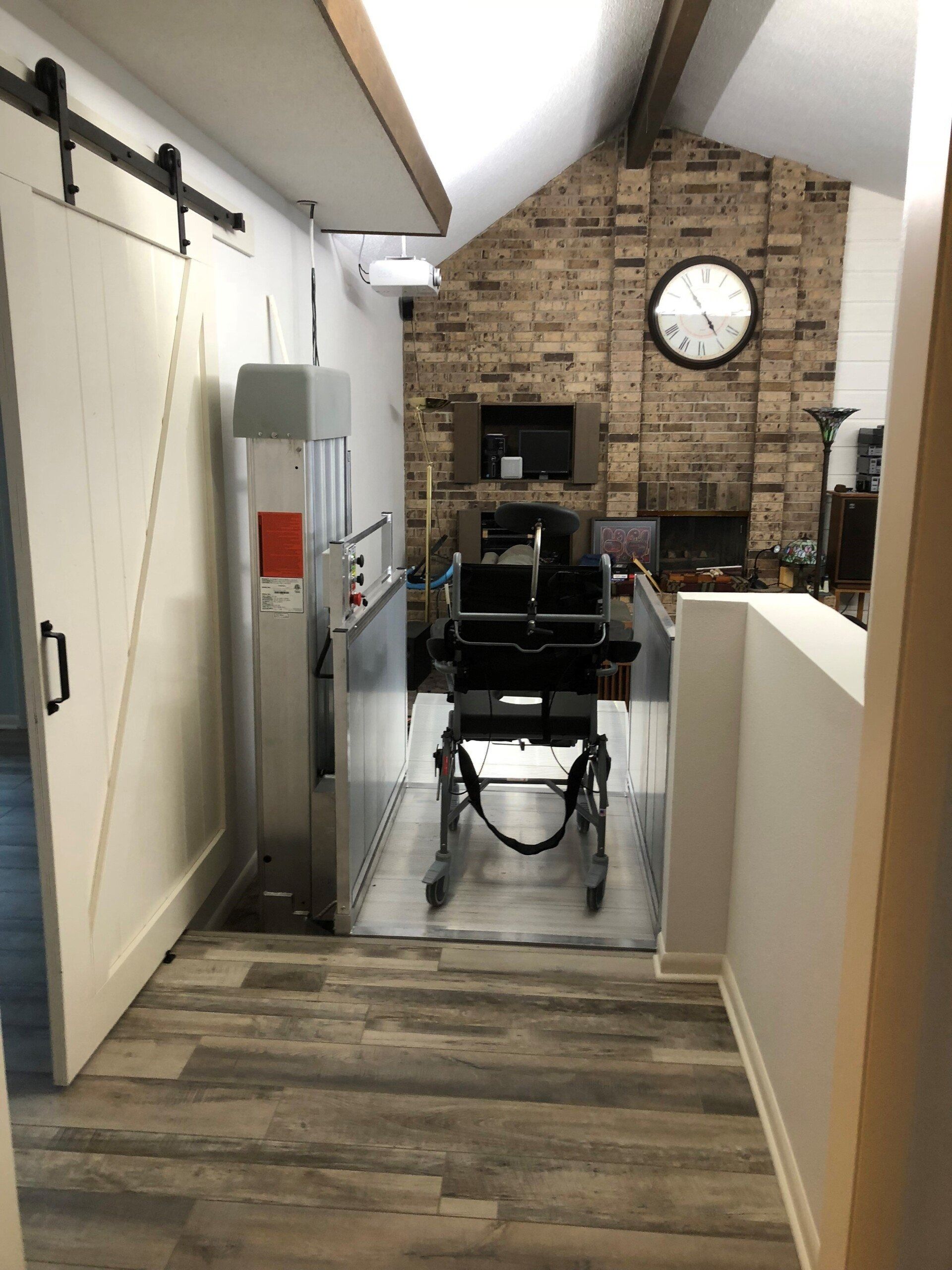 Indoor wheelchair lift next to a barn door, leading to a living room with a fireplace.